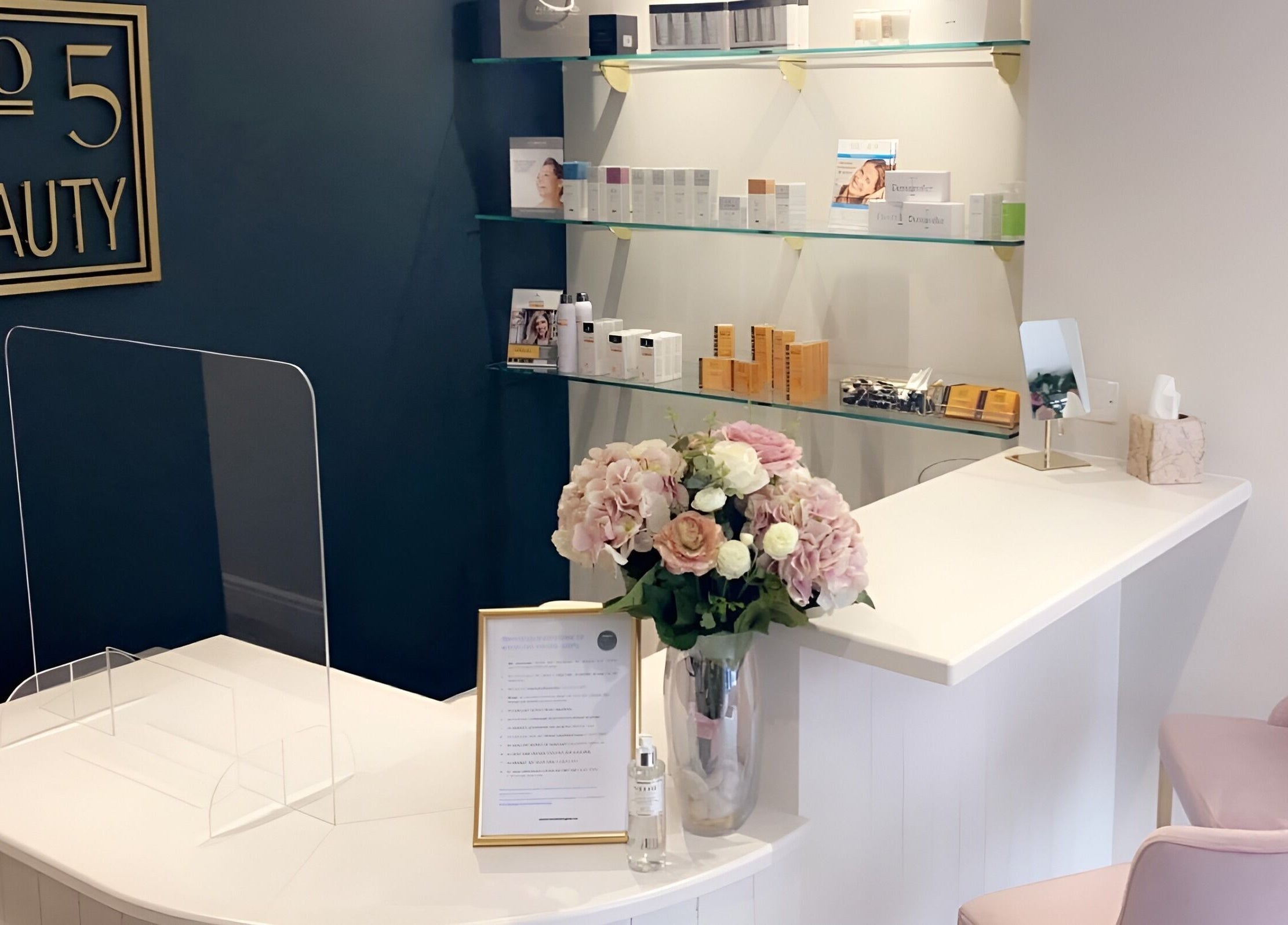 Elegant reception area at No 5 Beauty in Wetherby, England, GB featuring pink flowers and luxury products.