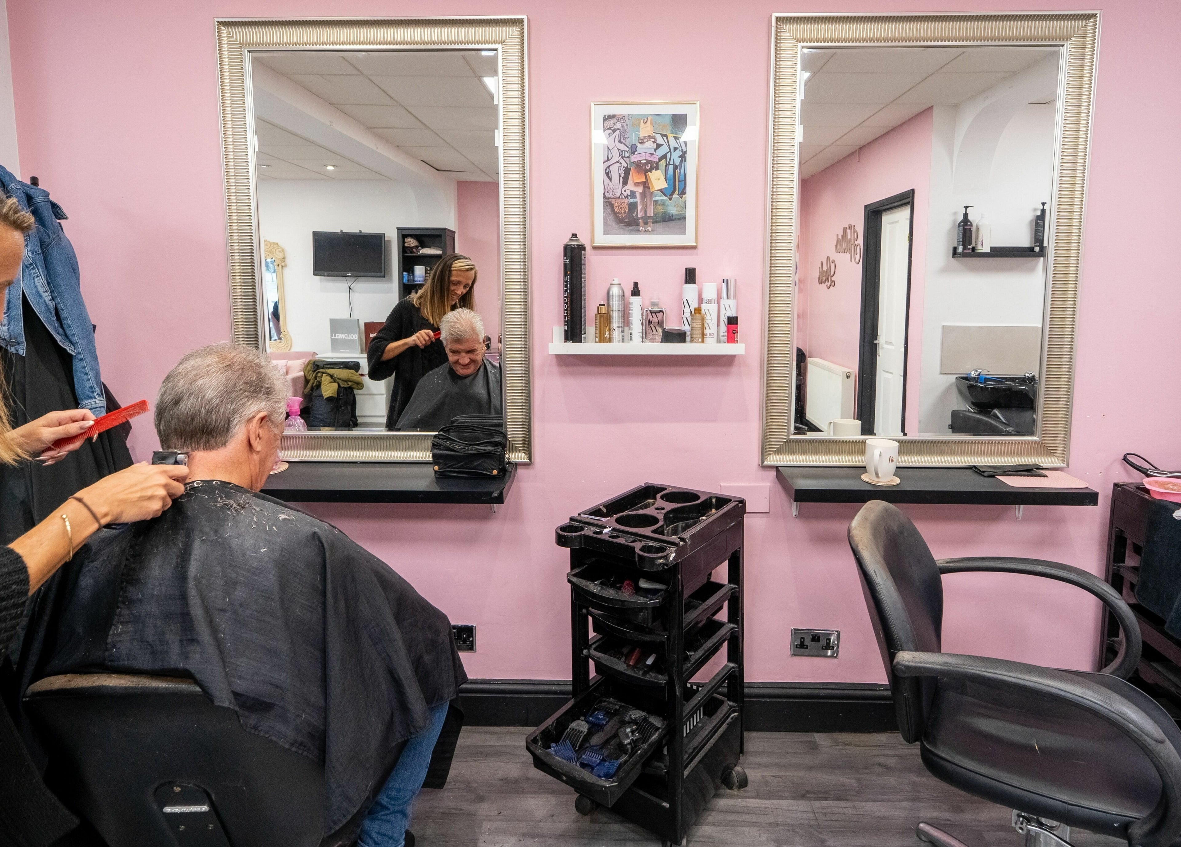Hair stylist working on client at Hollieslocks Salon, Hornchurch, England, GB. Pink walls and chic decor.