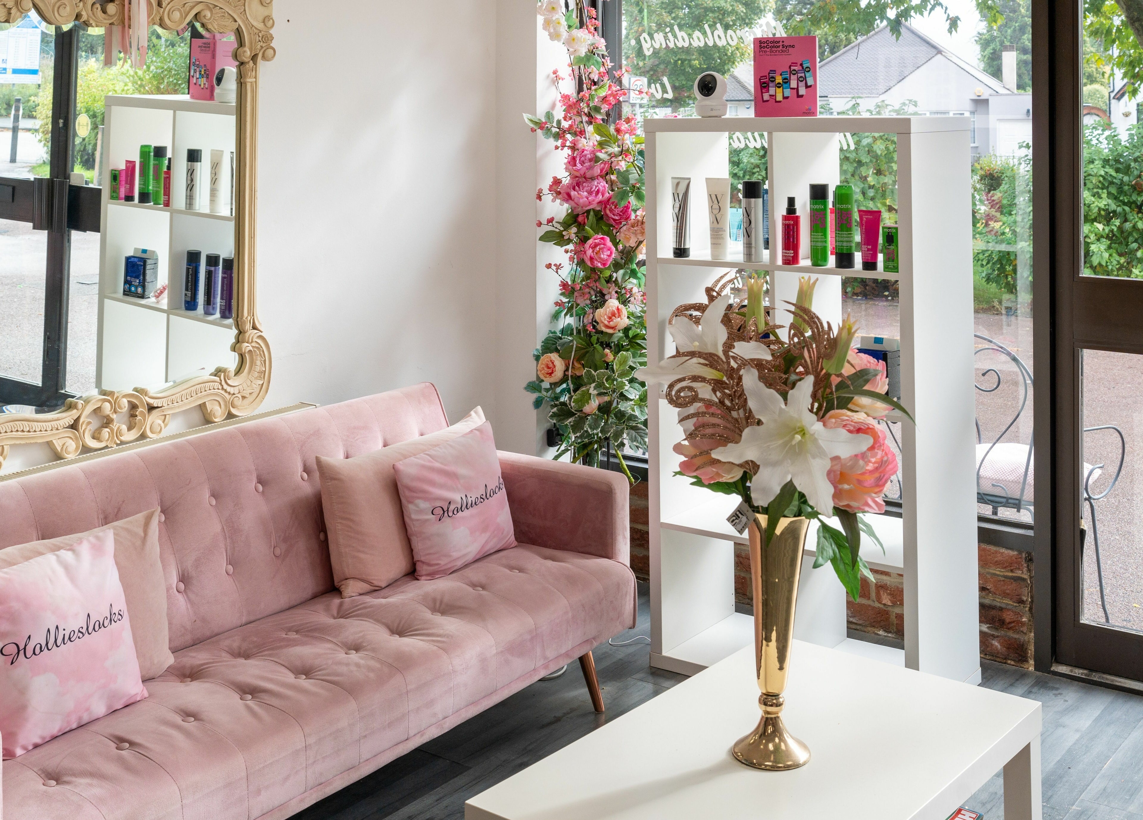 Cozy chic interior of Hollieslocks Salon, Hornchurch, England, GB, with plush seating and floral decor.