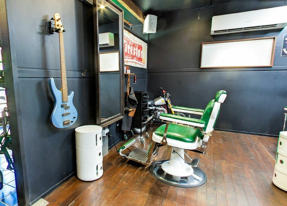 Modern interior of SHED Barbershop in Gladstone Central, Queensland, AU with vintage green chairs and elegant decor.