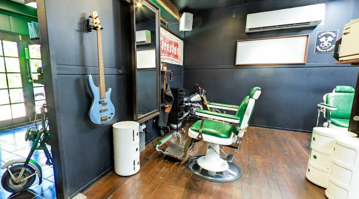 Modern interior of SHED Barbershop in Gladstone Central, Queensland, AU with vintage green chairs and elegant decor.