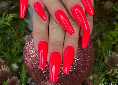 Vivid red nails at Base Coat Melkbos, Cape Town, Western Cape, ZA, with festive greenery background.