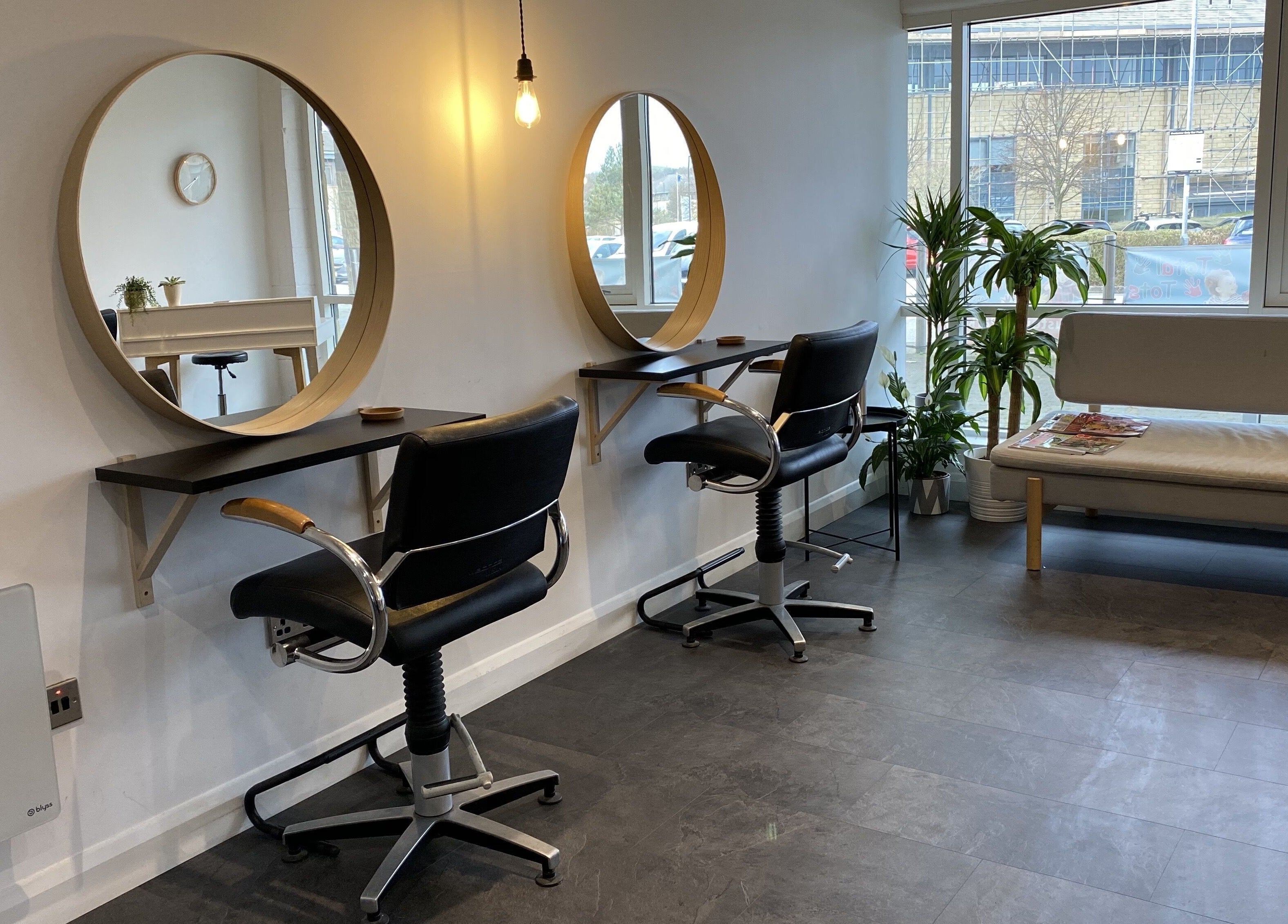 Interior of Fika Hair - Caton Road, Lancaster. Elegant salon with mirrors, chairs, and natural light.