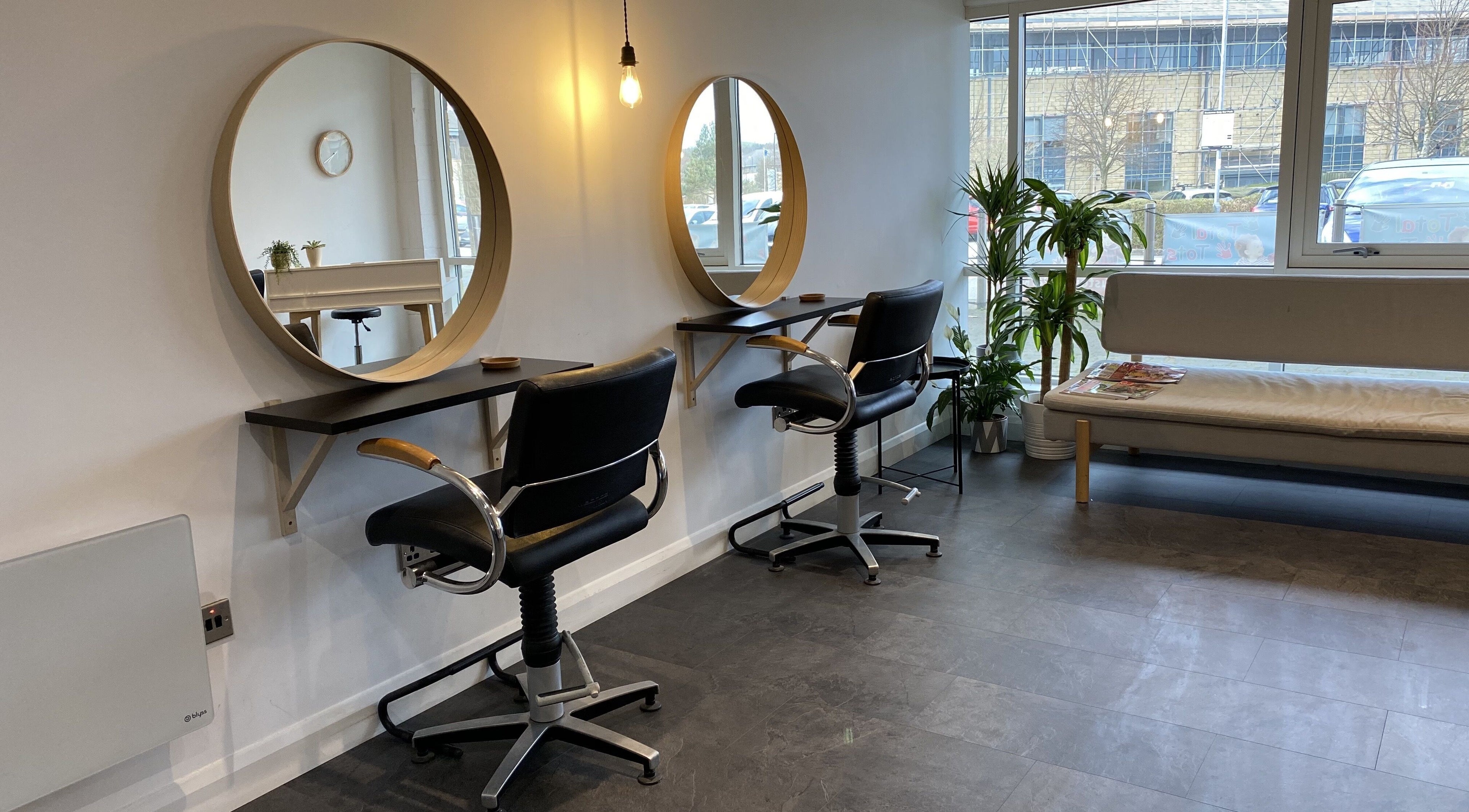 Interior of Fika Hair - Caton Road, Lancaster. Elegant salon with mirrors, chairs, and natural light.