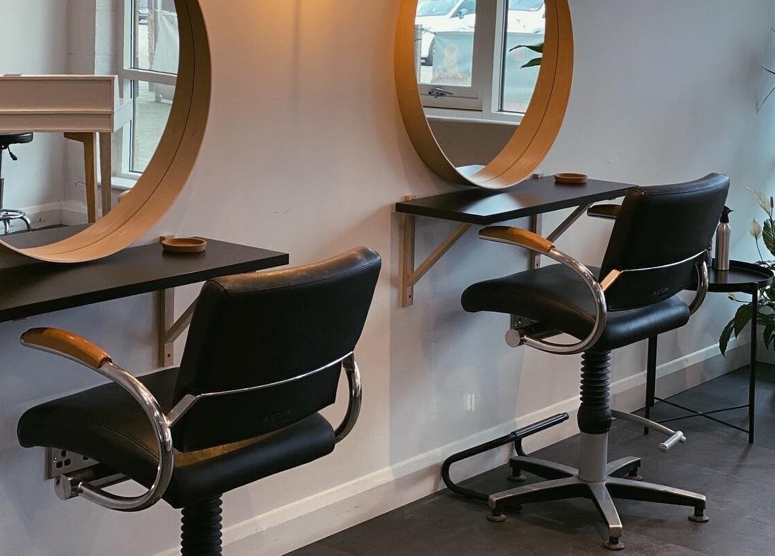 Modern styling stations at Fika Hair - Caton Road in Lancaster, England, GB with black chairs and wooden mirrors.