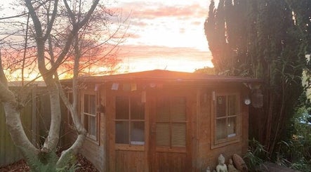 Peaceful garden retreat at The Massage Place, Glastonbury, England, GB, with a sunset backdrop and calming atmosphere.