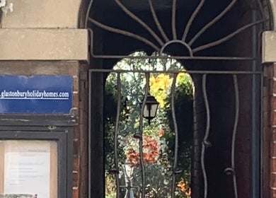 Elegant archway entrance at The Massage Place, Glastonbury, England, GB with surrounding greenery.