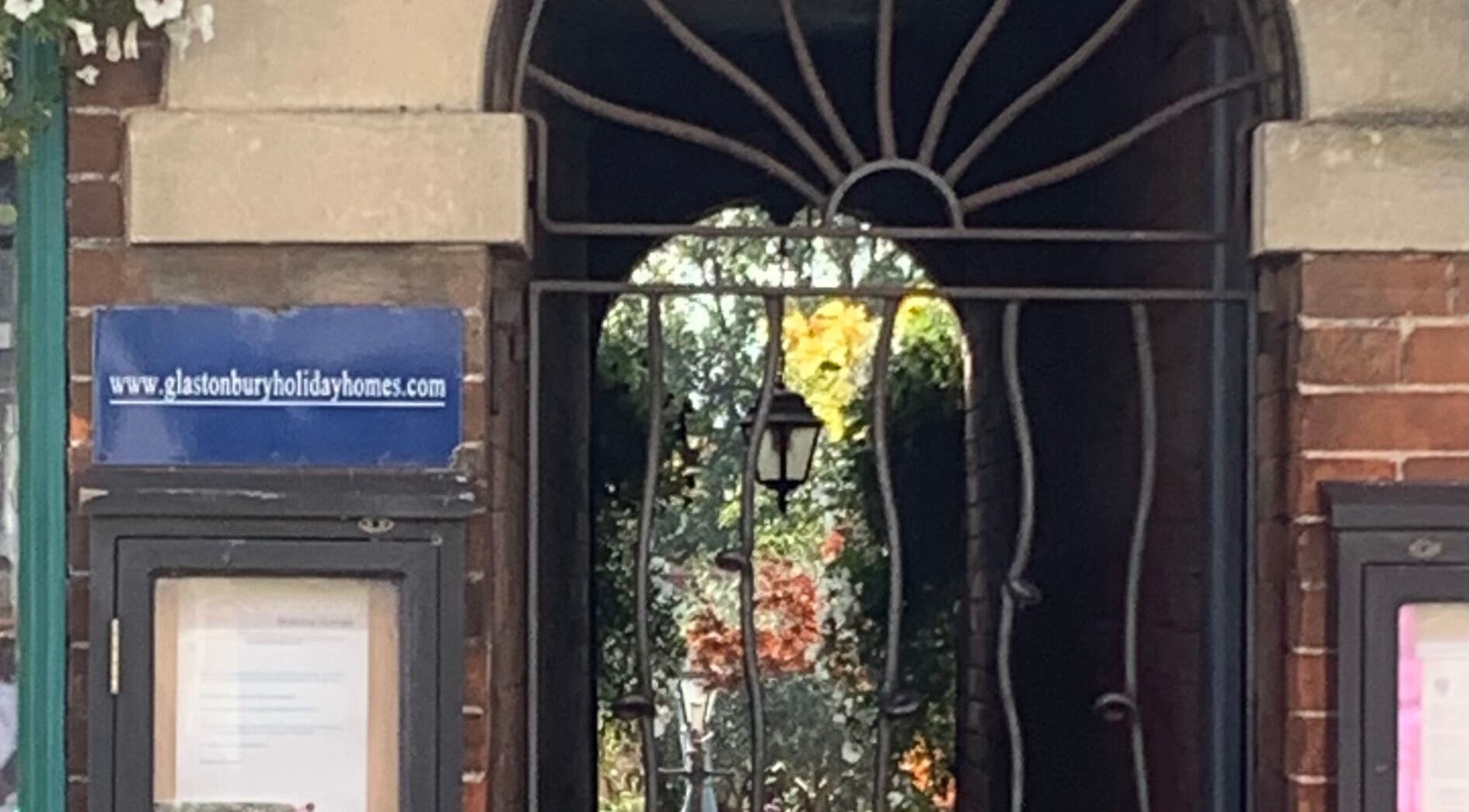 Elegant archway entrance at The Massage Place, Glastonbury, England, GB with surrounding greenery.