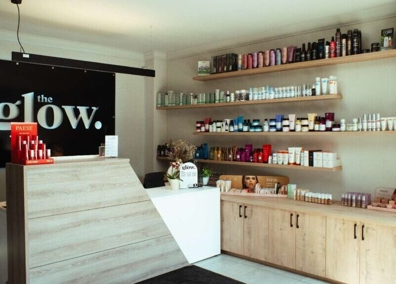 Reception area at The Glow, Benoni, Gauteng, ZA showcasing beauty products on wooden shelves.