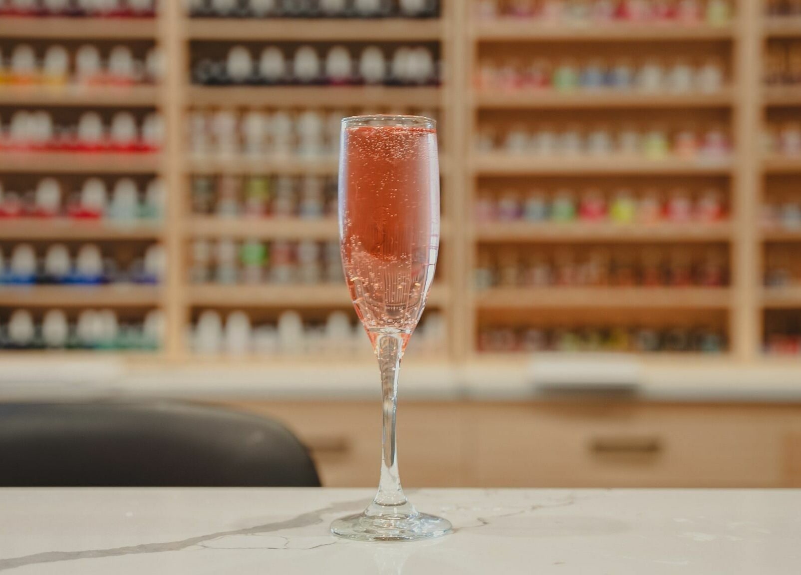 A glass of bubbly champagne at Crave Spa Westshore Marina in Tampa, Florida, US, with colorful polish display.