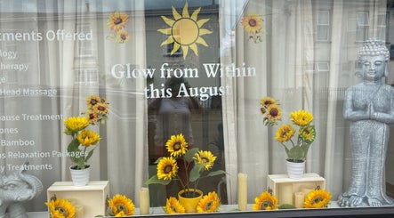 Vibrant sunflowers and a serene statue adorn Balancing Touch Complementary Therapies in Risca, Wales, GB.