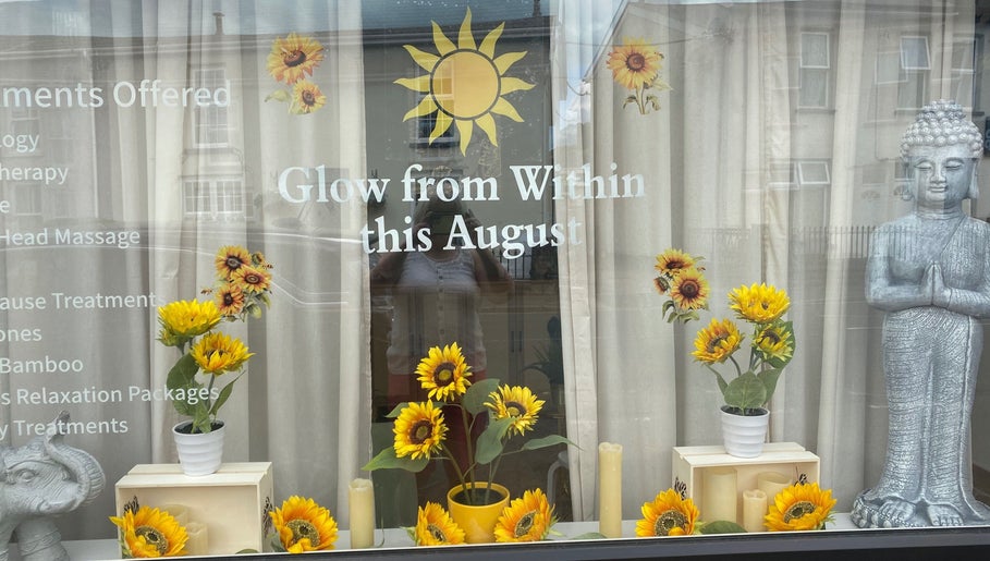 Window display at Balancing Touch Complementary Therapies, Risca, Wales, GB with sunflowers and Buddha statue.