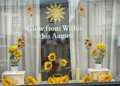 Window display at Balancing Touch Complementary Therapies, Risca, Wales, GB featuring sunflowers and a Buddha statue.