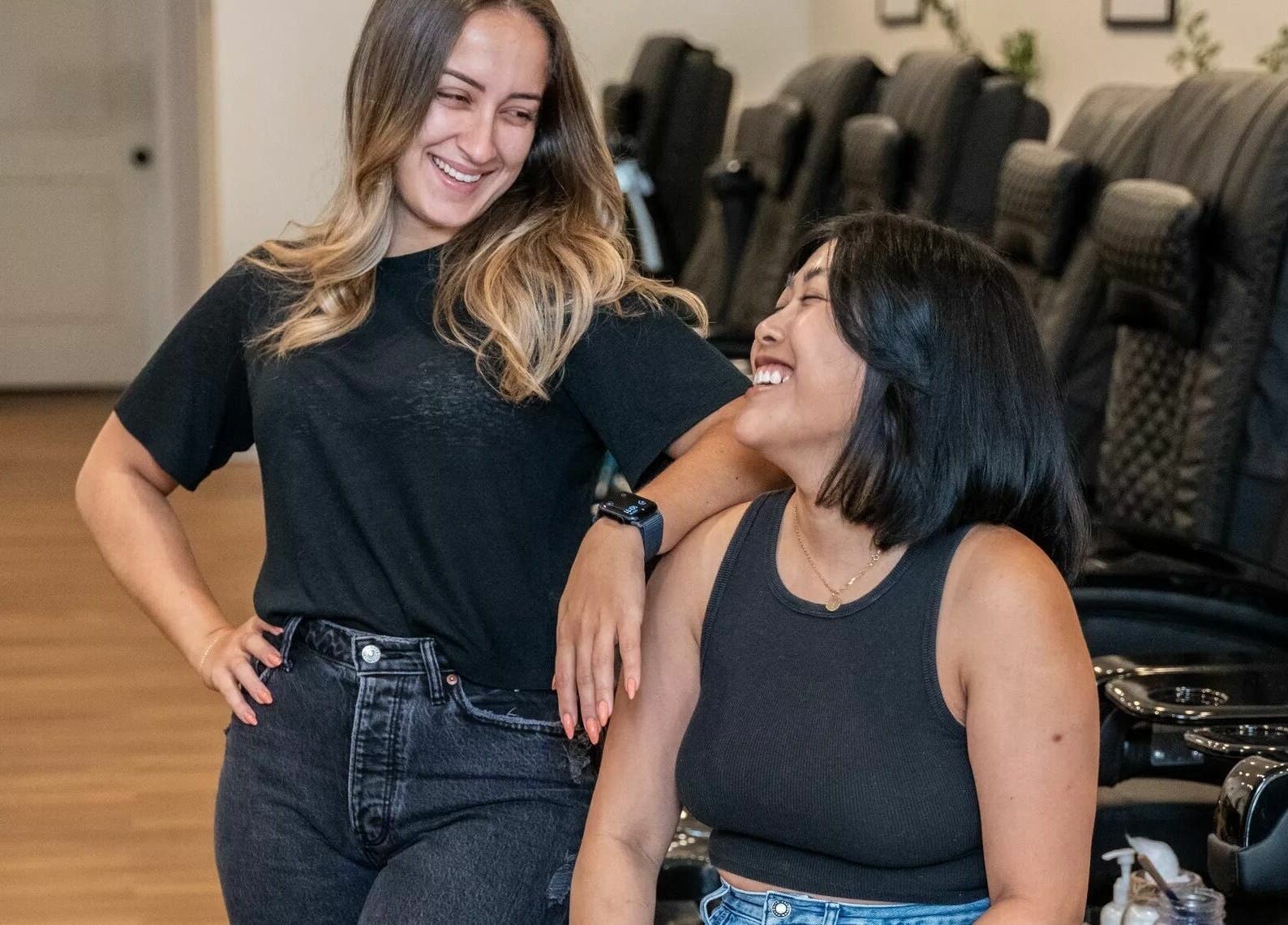 Two women smiling at Onyx Nail Bar, Voorhees Township, New Jersey, US, with stylish nail chairs in background.