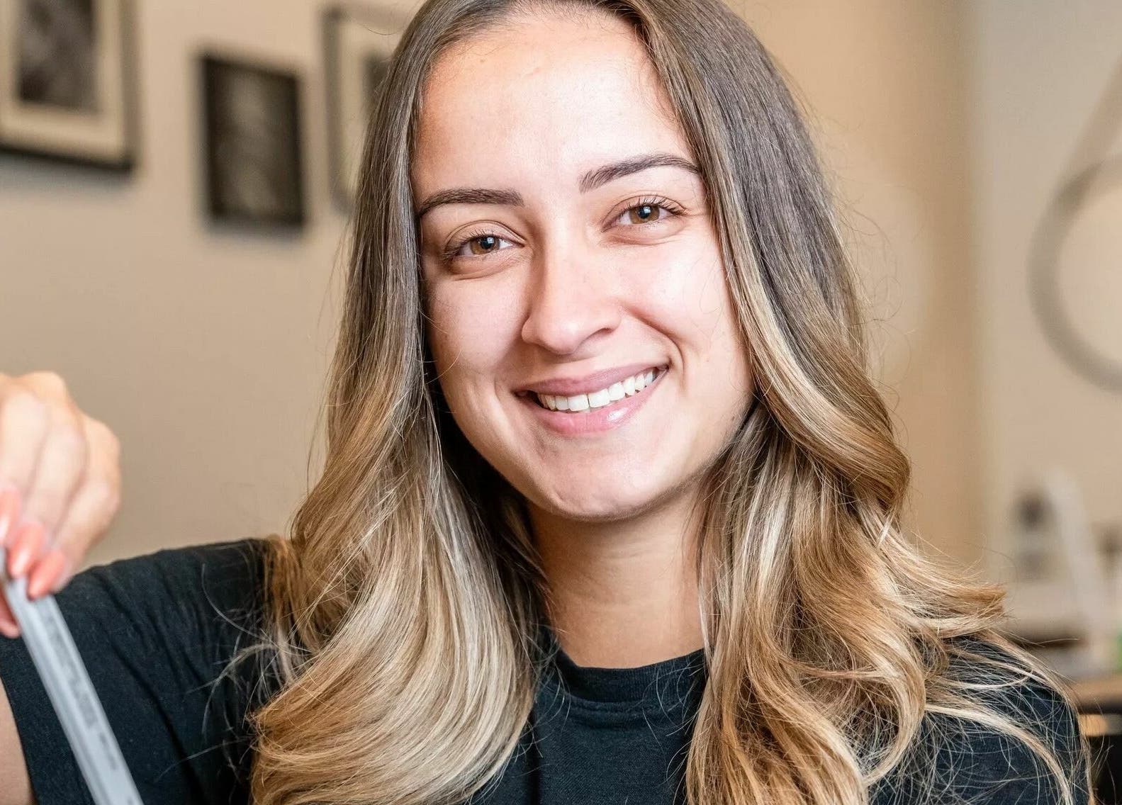 Smiling stylist at Onyx Nail Bar, Voorhees Township, NJ, US, holding nail care tool.