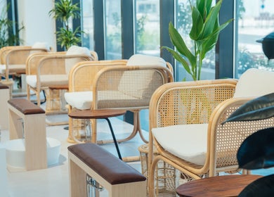 Stylish seating area at Boho Salon DXB in Dubai, Dubai, AE with elegant wooden chairs and lush greenery.