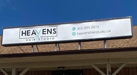 Heavens Hair Studio signboard at Fort Erie, Ontario, CA displayed against a clear blue sky.
