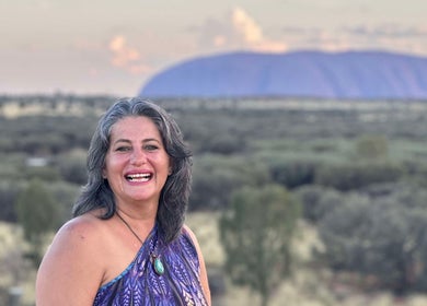 Smiling woman at Earth Magic with Suzie Maxwell, Currumbin Waters, Queensland, AU, with scenic outback backdrop.