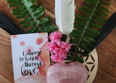 Decorative display with pink flowers, feathers, and love card at Earth Magic with Suzie Maxwell, Currumbin Waters, Queensland, AU.