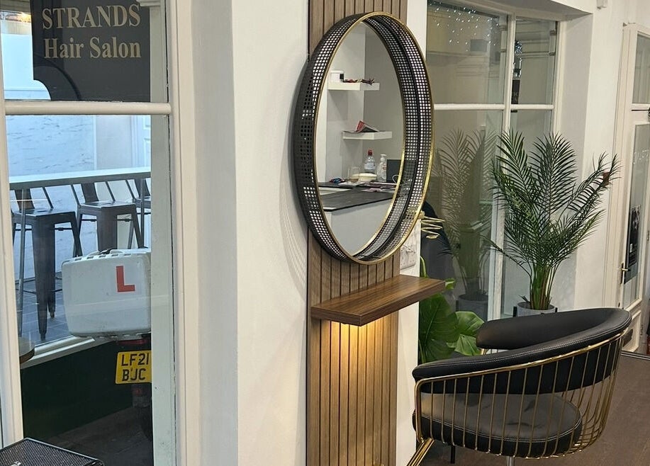 Modern salon interior at Strands salon Newport Pagnell -Jen, featuring stylish chairs and a vibrant plant in Newport Pagnell, England, GB.