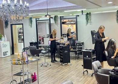 Stylish interior of Salon 971 in Dubai, AE, featuring luxury chandeliers and professional hairstylists at work.