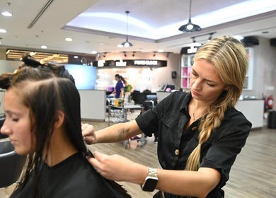 Hairstylist at Salon 971 in Dubai, Dubai, AE expertly trims a client's hair in a modern salon setting.