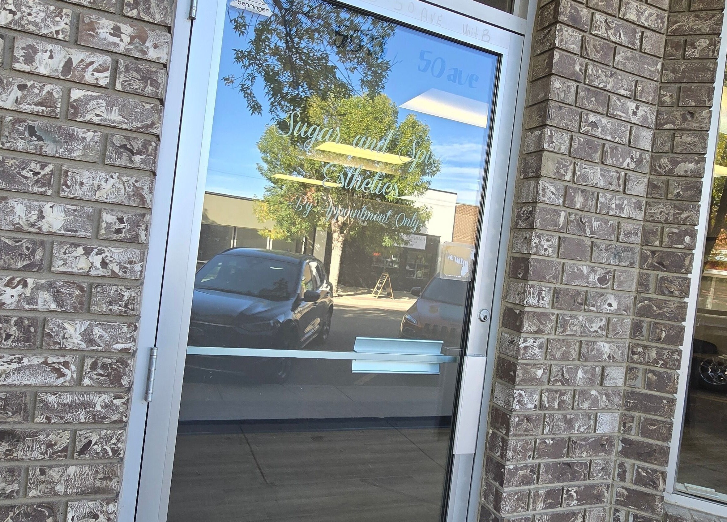 Entrance to Sugar and Spice Esthetics in Ponoka, Alberta, CA showing a glass door with reflection.