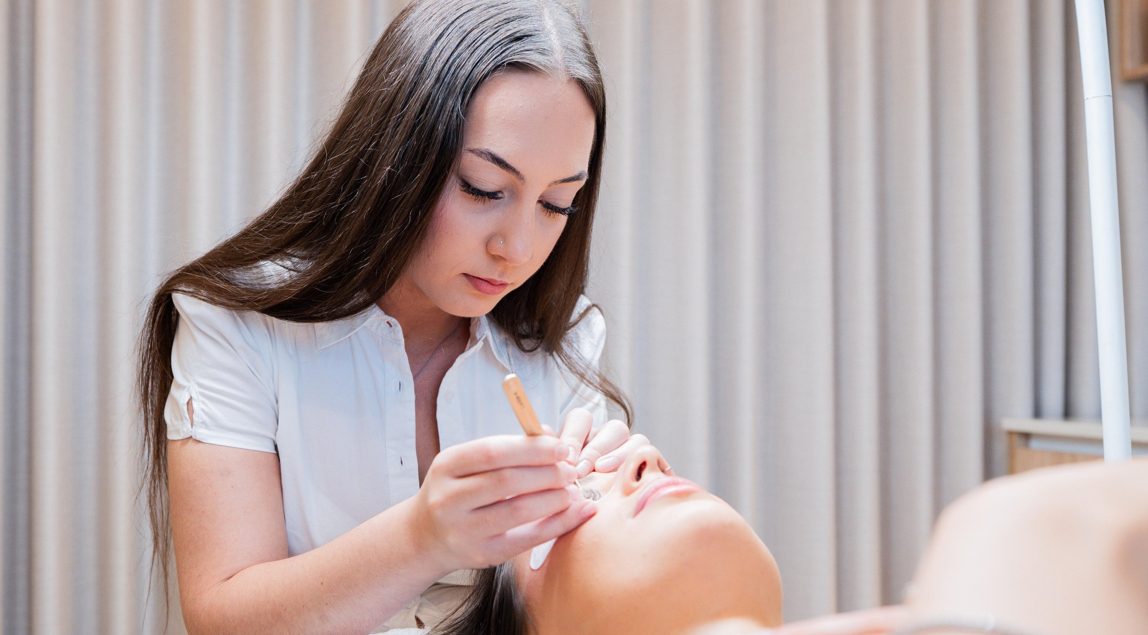 Lash artist at QLash Studio in Forest Lake, Queensland, AU expertly applies eyelash extensions.