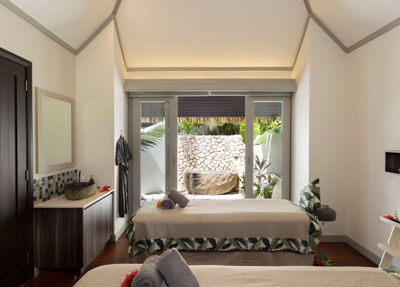 Serene spa room at Sofitel Fiji Resort & Spa on Denarau Island, showcasing elegant decor and garden view.