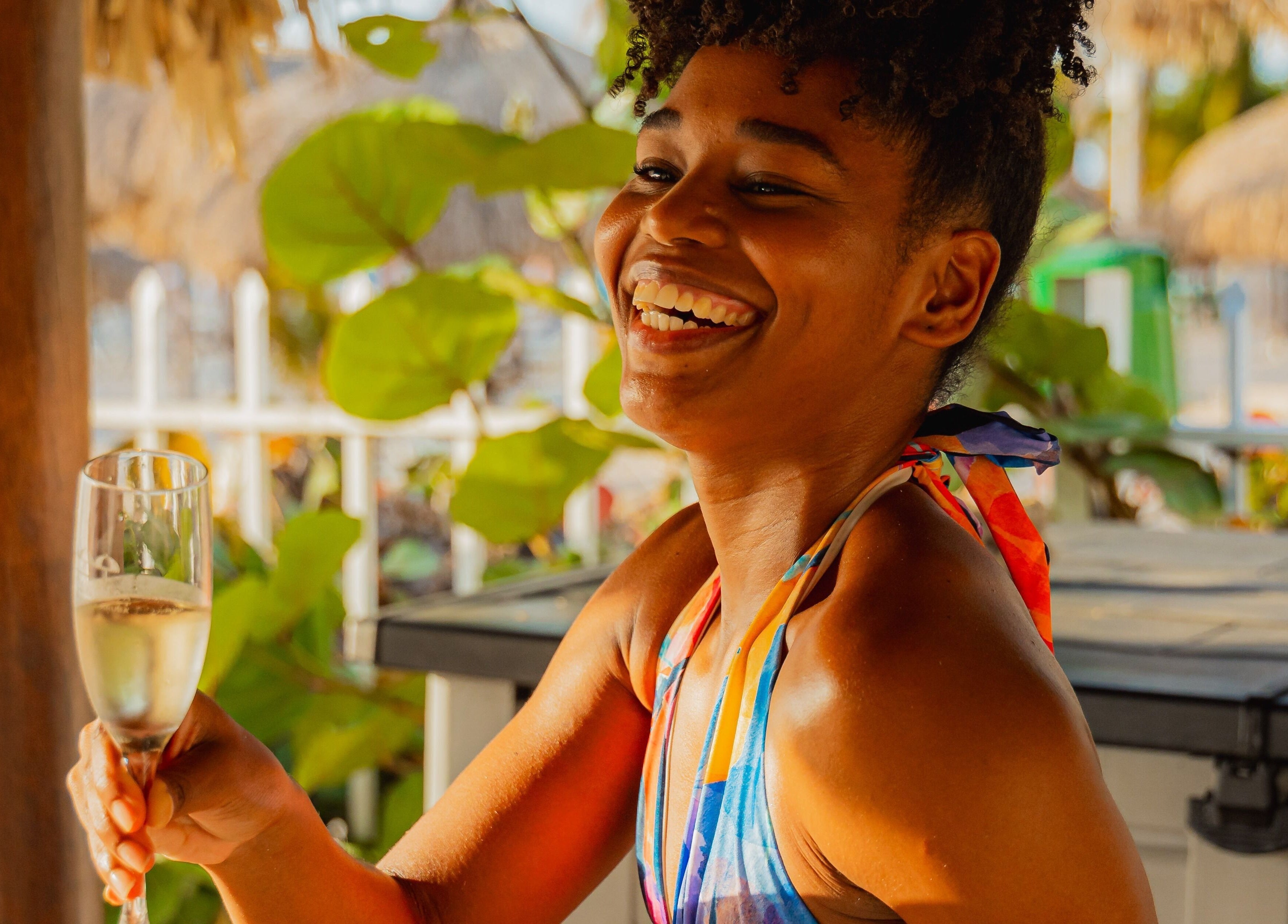 Joyful woman enjoying a drink at Purun Spa in Oranjestad, AW amidst a serene, lush setting.