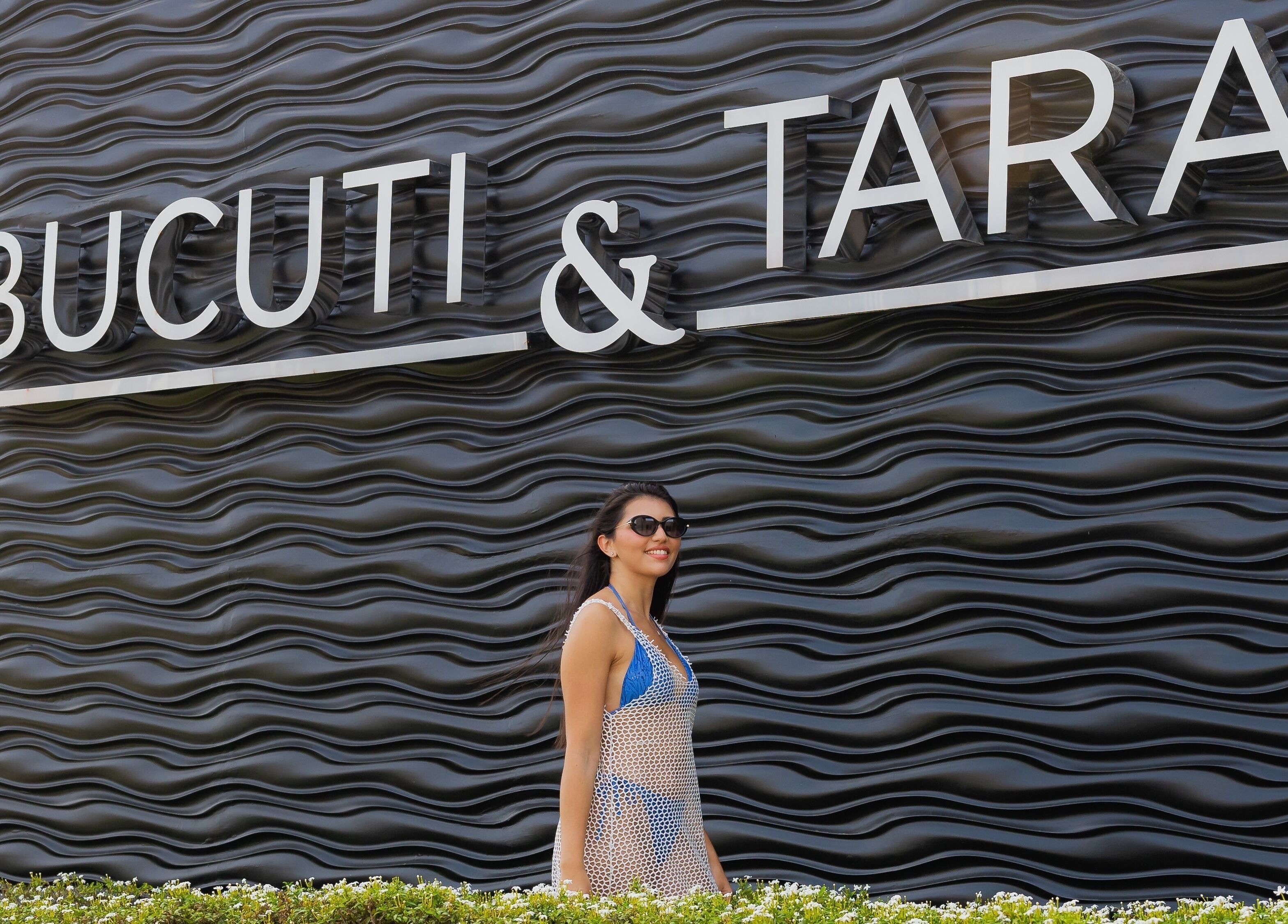 Person walking by stylish wave-patterned wall near Purun Spa, Oranjestad, AW.