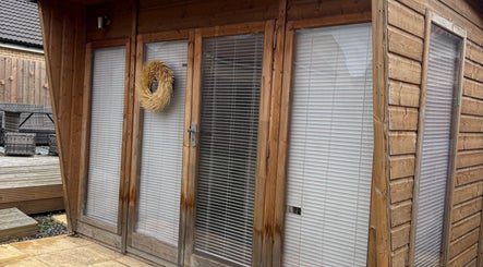 Rustic wooden exterior of Beauty by Chloe venue in Hopton, England, GB with woven wreath and modern blinds.