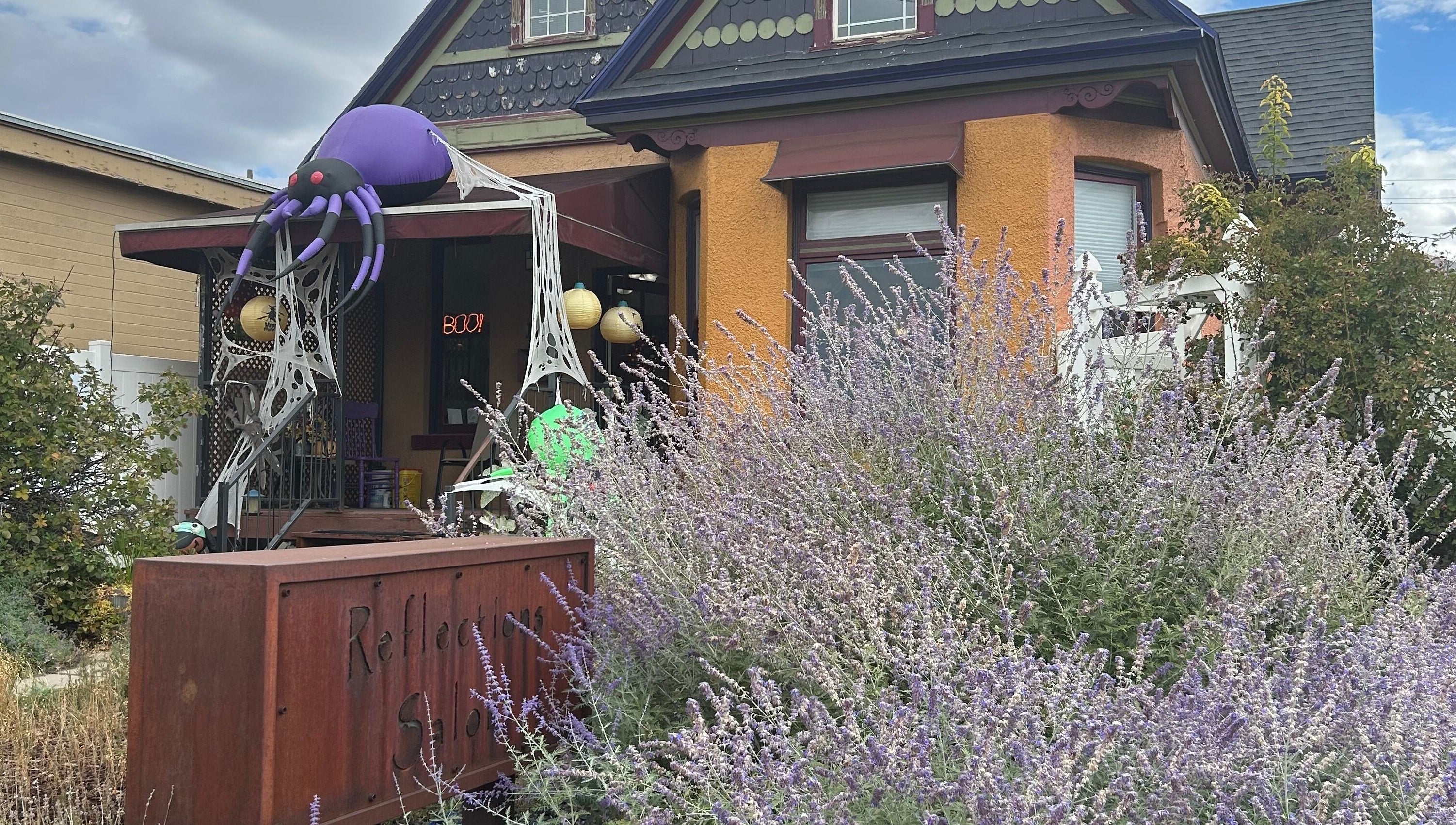 Charming exterior of Reflections Salon and Spa in Salt Lake City, Utah with festive decor and lush lavender.