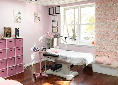 Millennium Beauty Studio's pink-themed room in New York, New York, US, featuring a treatment bed and floral decor.