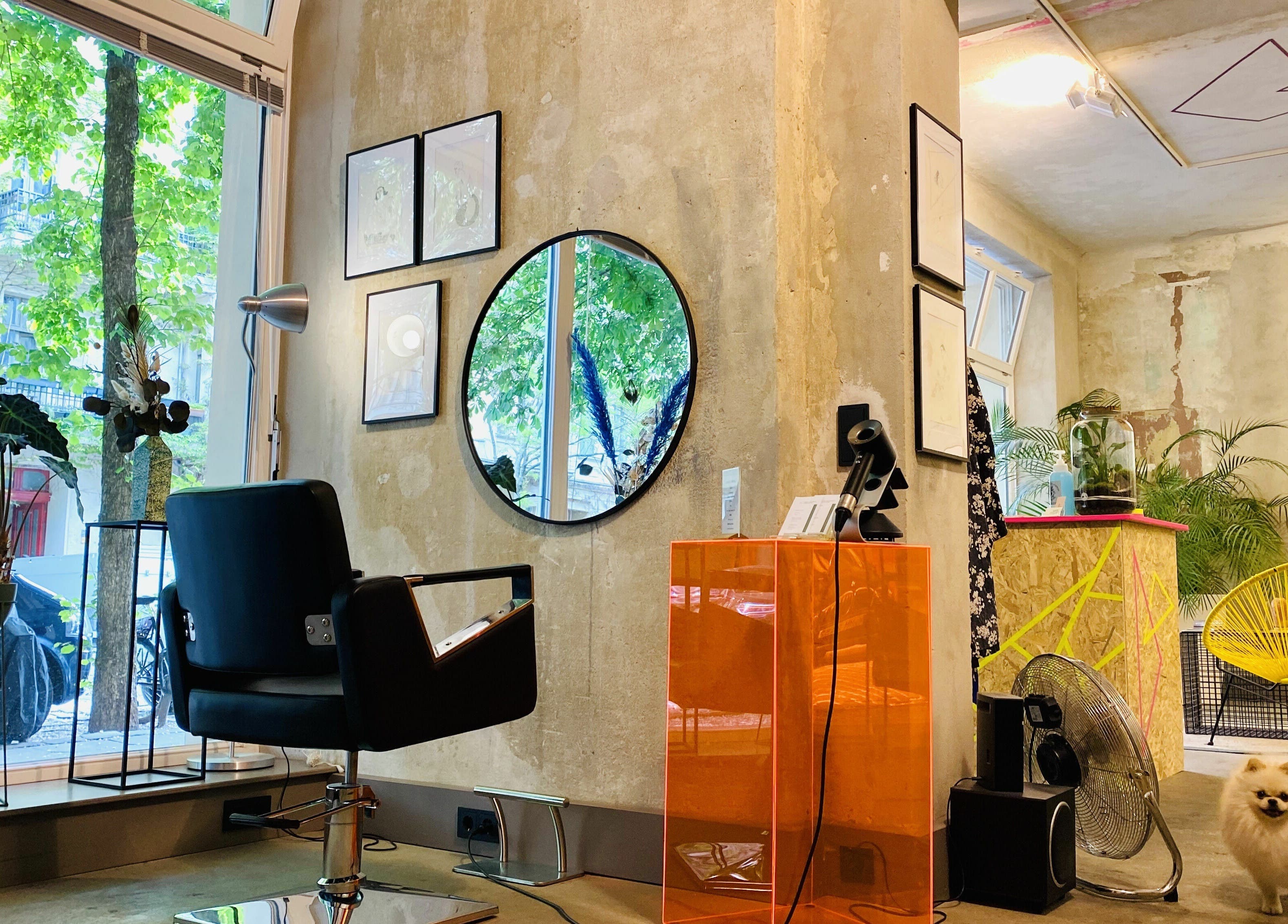 Inside Marc-Antoine Hairstudio Gallery, Berlin, Berlin, DE. Stylish chair facing mirror with lush green views.