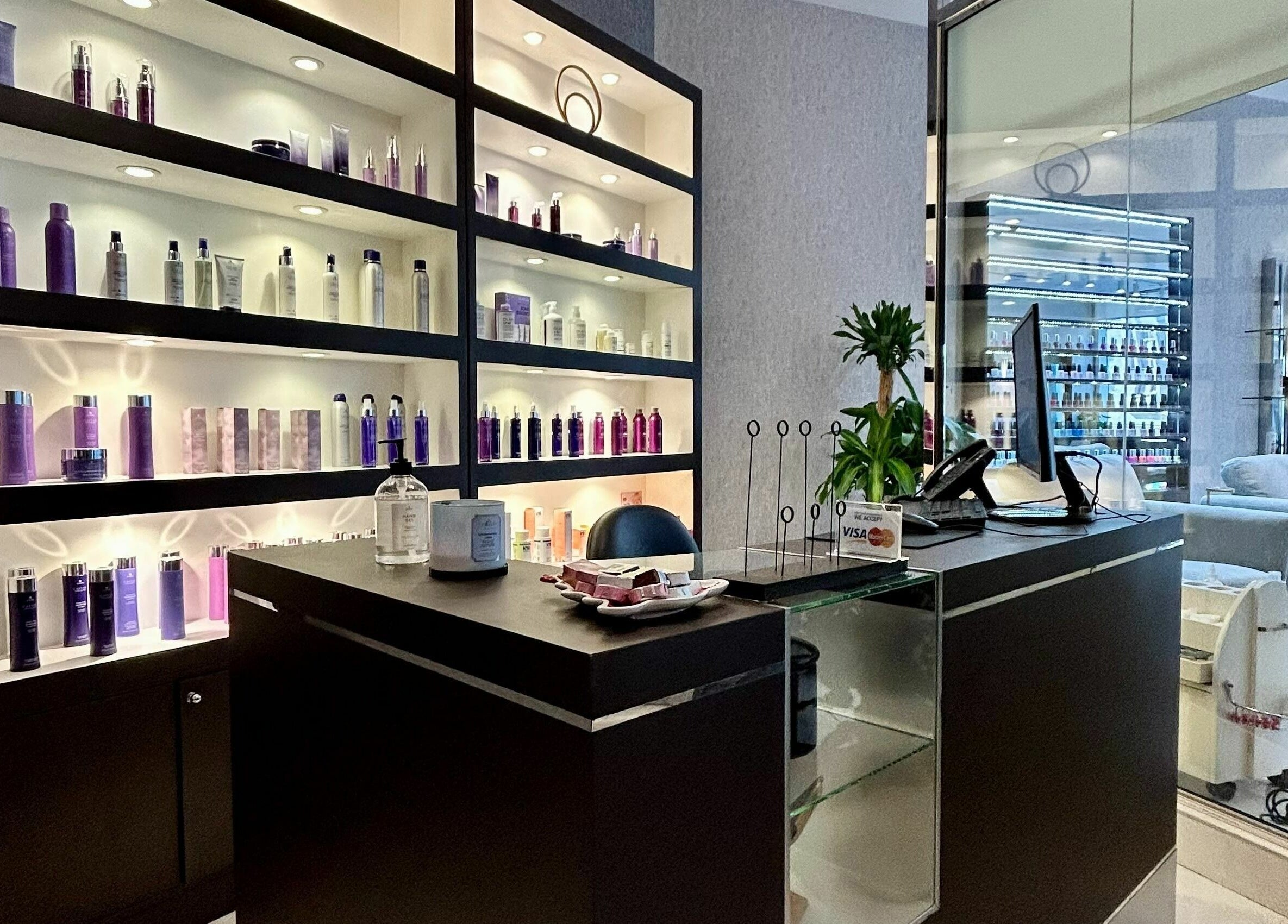 Reception area at Venere By Ann Ladies Salon in Abu Dhabi, showcasing products on sleek, lit shelves.
