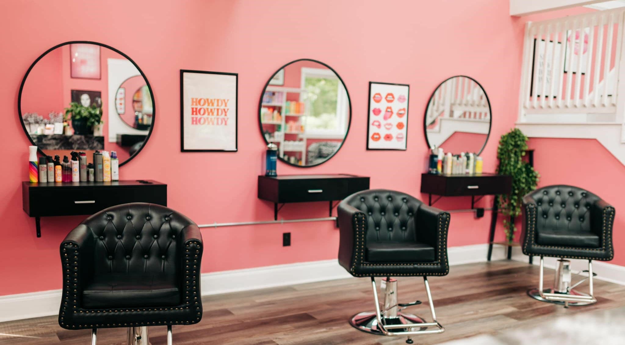Elegant styling chairs at Cheeky Hair Studio, Weymouth, Massachusetts, US with pink walls and modern decor.