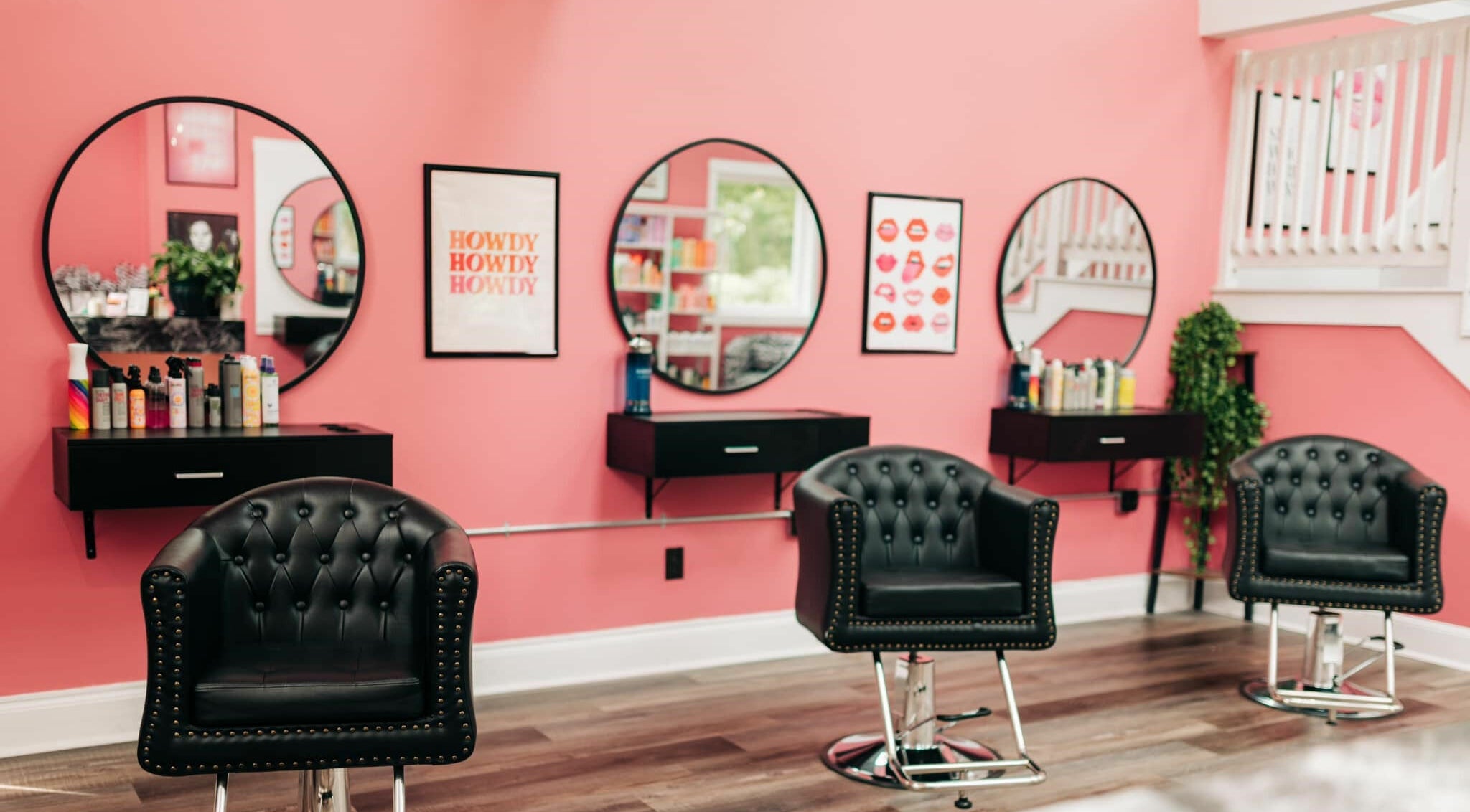 Elegant styling chairs at Cheeky Hair Studio, Weymouth, Massachusetts, US with pink walls and modern decor.