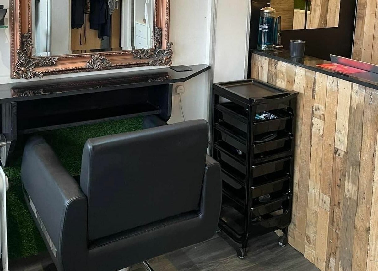 Modern salon station at Platform 169, Exeter, England, GB. Features styling chair, mirror, and wooden decor.