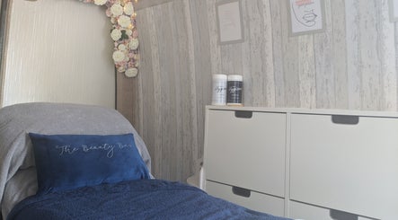 Cozy interior of The Beauty Bus in Oxfordshire, GB featuring a plush treatment bed and floral decor.