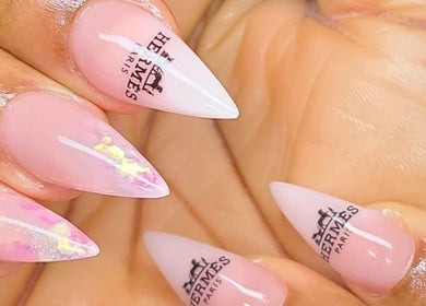 Stylish Hermès-themed nails at Myrie Beauty in Whitby, Ontario, CA. Elegant pink manicure with logo design.