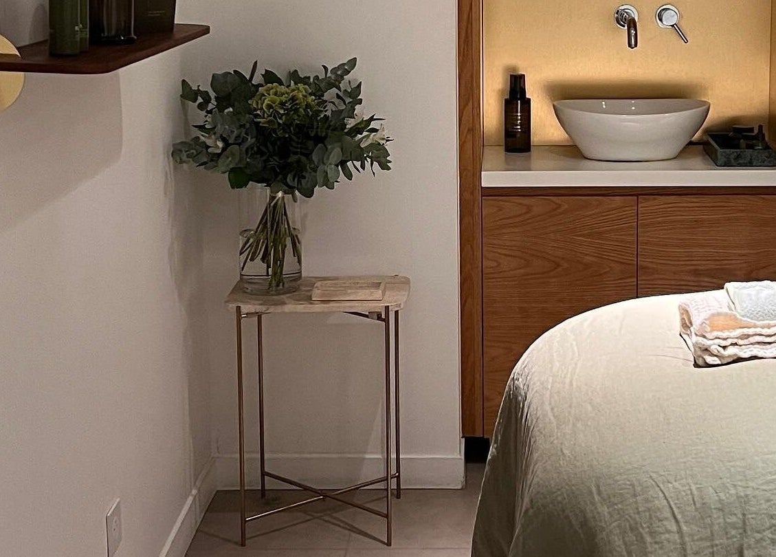 Tranquil therapy room at Fields of Yarrow Berawa, Bali. Cozy bed, lush flowers, and elegant decor.