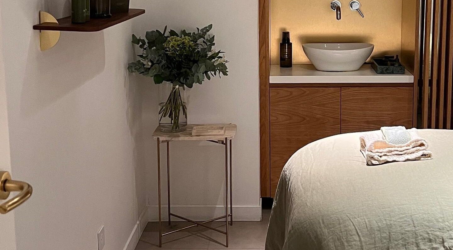 Tranquil therapy room at Fields of Yarrow Berawa, Bali. Cozy bed, lush flowers, and elegant decor.