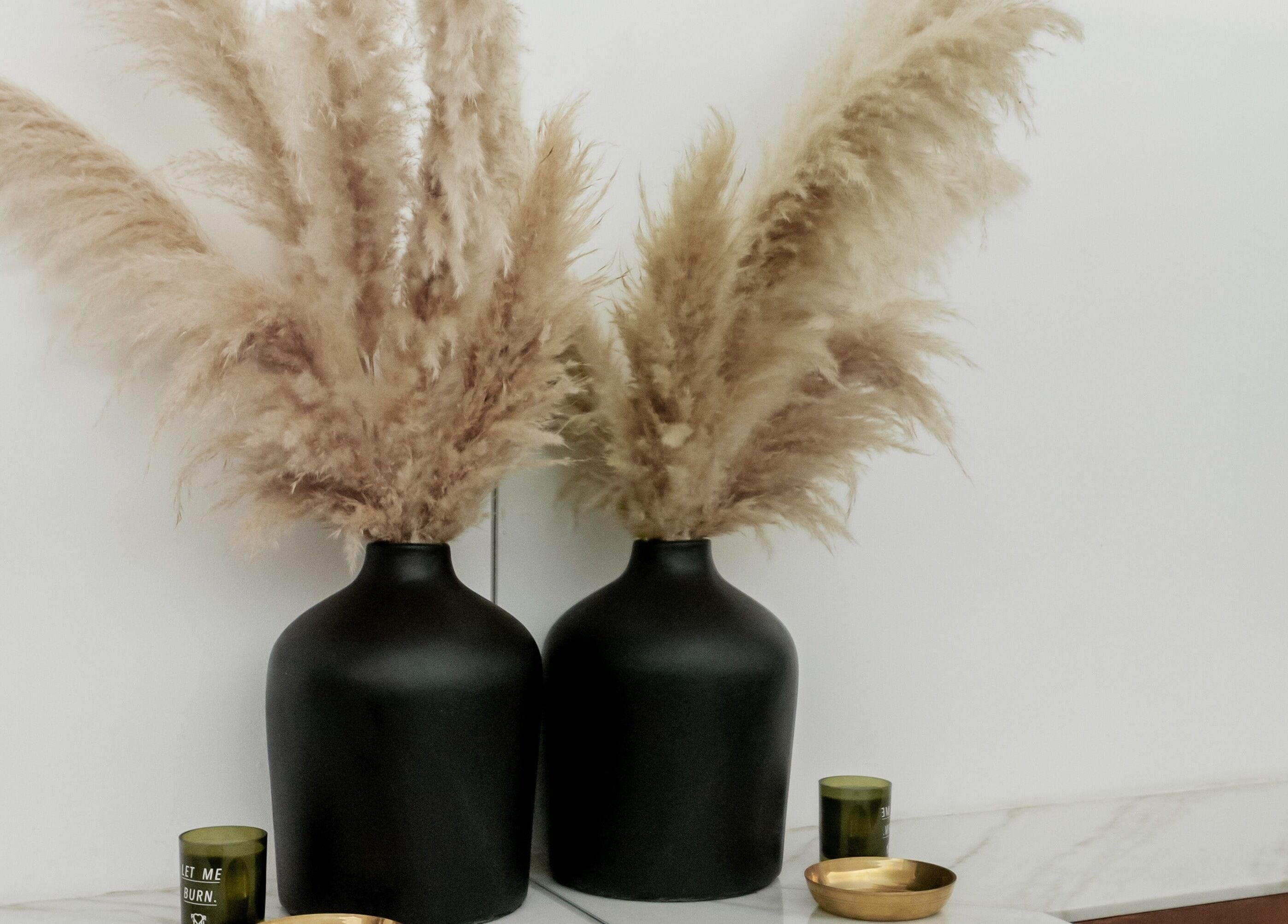 Stylish pampas grass in black vases on marble counter at Fields of Yarrow Berawa, Bali, Bali, ID.