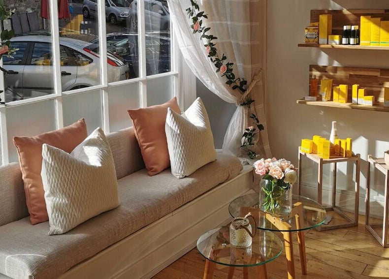 Cozy seating at River and Rose in Dartmouth, England, GB, with sunlit shelves displaying wellness products.