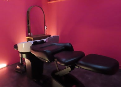 Relaxing salon chair at Maris Gina, Shibuya City, Tokyo, JP, showcasing sleek black design and vibrant pink walls.