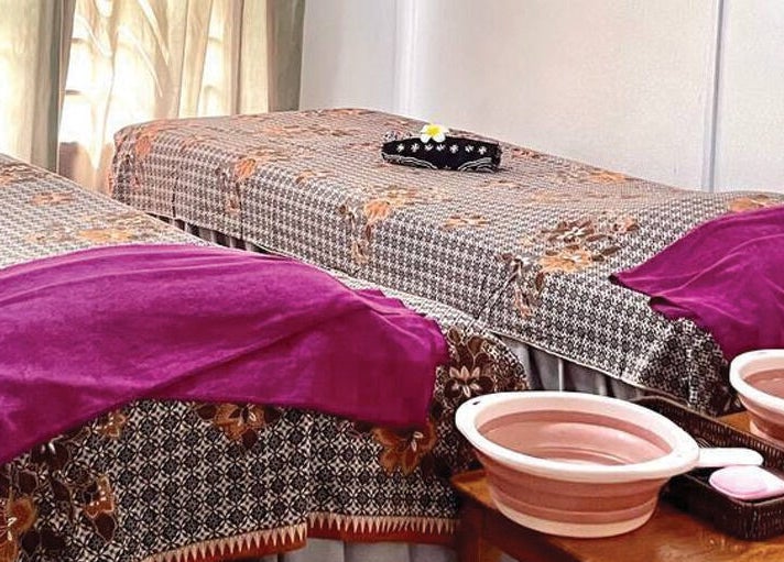 Double massage tables with purple towels at Belaian Emas Spa, Putrajaya, Putrajaya, MY, inviting a serene experience.