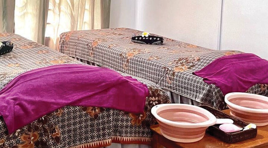 Double massage tables with purple towels at Belaian Emas Spa, Putrajaya, Putrajaya, MY, inviting a serene experience.
