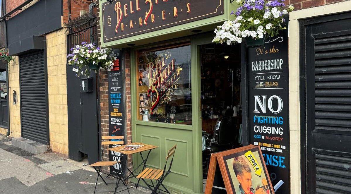 Charming exterior of Bell St. Barbers in North Shields, England, GB adorned with flowers and vintage signs.