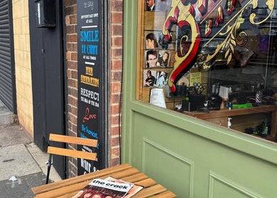Exterior of Bell St. Barbers with vintage sign and outdoor seating in North Shields, England, GB.